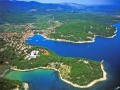 Jelsa (Wyspa Hvar) jest perełką pośród malowniczych, dalmatyńskich miejscowości. Wyspa Hvar uznawana jest za jedną z najpiękniejszych wysp w całej Chorwacji. Często określa się ją mianem „chorwackiej Madery”. Niewątpliwie uroku dodaje także położenie w pobliżu archipelagu Wysp Piekielnych.

Miejscowość Jelsa połączona jest piękną 1,5 km nadmorską promenadą Vrboską, a zlokalizowana na północnym wybrzeżu wyspy Hvar. Od strony południowej chronią ją wzgórza: Vrh, Samotorac, Gozd, a od północy otacza ją góra Burkovo.

Jelsa to najodpowiedniejsze miejscem do kąpieli zarówno morskich jak i słonecznych. W koło gorący piach i zapierające dech w piersiach widoki skalistych urwisk, zatopionych pomiędzy wiecznie zielonymi lasami iglastymi. Rejony Jelsy słyną, ze wspaniale rozwiniętego wybrzeża, z wieloma bajecznymi wysepkami. Posiadają one olbrzymią ilość urokliwych zatoczek, gdzie można zaznać dużej dawki spokoju i relaksu.
 
Panujący tam przyjazny klimat, łagodny wietrzyk, gorące lata, ciepłe zimy, sprzyjają podróżom i spędzaniem wakacji w tym, jakże cudnie, położonym zakątku świata. Każdemu odwiedzającemu oferowana jest, cisza i orzeźwiający wypoczynek, w trakcie wakacyjnego upału. Cudowne stają się spacery brzegiem morza, rozkoszowanie się zapachem sosnowego lasu i wycieczki po zadbanych i czystych wioskach.

Na turystów wszędzie czekają miłe niespodzianki. Na każdym kroku napotkać można coś interesującego. Zachwyca nie tylko bujna śródziemnomorska przyroda i pachnące pola lawendy, rozmarynu, wspaniałe gaje oliwne, słodkie winnice i roślinność śródziemnomorska, ale również długa historia, regionu i zabytki sięgające czasów antycznych, które widać wszędzie, dokądkolwiek się udamy. Wskazują na to pozostałości wiejskich posiadłości, głównie z czasów greckich i średniowiecznych (Villa Rustica), gdzie doskonale zachowała się architektura wąskich kamiennych uliczek i placyków. Pierwszy kościół w mieście Św. Jana powstał w XVII w. Zabytki widoczne są również w innych kościołach, na miejskich ryneczkach, uliczkach oraz w wielu innych miejscach.


Miasto świętuje dokładnie 130 letnią tradycję turystyczną. Najstarszy Hotel Jardan otwarto już w 1911 roku. Na lata 60 - te XX przypada czas budowy nowych pensjonatów, apartamentów, obiektów rekreacyjnych, restauracji, dyskotek. Turystyka w tym czasie stała się głównym sposobem zarobkowym na wyspie. Od trzeciego wieku p. n. e do lat współczesnych, mieszkańcy zajmują się uprawą winorośli oraz drzew oliwnych. Dzięki temu wspaniale rozwinięte rolnictwo dobrze uzupełnia się z ofertą turystyczną miasta.
 
W 1991 roku wyspa Hvar podpisała Deklarację Wysp Dalmatyńskich. Dzięki temu znajduje się w czystej jak łza, ekologicznej strefie. W całym rejonie możemy korzystać z krystalicznej wody i oddychać równie czystym powietrzem.

Najciekawsze miejsca do odwiedzenia w Jelsa to:

• Ogród Perivoj, powstały w ok 1870 r.

• Przepiękny jak twierdza wzmocniony Kościół św. Marii z 1331r. W tym momencie pod wezwaniem św. Fabiana i Sebastiana.

• Oktagonalny kościół św. Jana

• Kościół św. Michała z 1463r.

• Plac Św. Ivana i należącą do niego XV -wieczną kaplicę z miniaturowym placem i otaczającymi go malowniczymi domami z XV-XVII w.

• Ruiny Civitas Vetus Ielsae, czyli pozostałości starego miasta Jelsa.

• Tor - zlokalizowana na wzgórzu położonym na południe od miasta, dobrze zachowana grecka wieża obserwacyjna z IV w. p. n. e.

• Grad (lub Galešnik) - ruiny twierdzy zburzonej w 1310 r. podczas nieudanego powstania przeciw Wenecji.

Pobyt w Jelsa, to również możliwość wspaniałego, aktywnego wypoczynku. Wachlarz zajęć sportowych jest bardzo szeroki. Możemy wybierać między mini golfem, koszykówką, wioślarstwem, siatkówką, nurkowaniem, kolarstwem, narciarstwem, tenisem, a bowlingiem. Każdy znajdzie coś dla siebie. W całym mieście znajdują się świetnie oznakowane ścieżki rowerowe, które namawiają nas do organizowania całodniowych wycieczek. Takie podróże na dwóch kołach umożliwiają szybkie przemieszczanie się i zwiedzanie innych miejscowości i pięknych zakątków na wyspie Hvar. Doskonałą wycieczką jest rejs na pobliskie wyspy Kornati i odwiedzenie Parku Narodowego Krka, znanego ze wspaniałych wodospadów z naturalnych barier.
 
Ponadto, ciepłe wieczory po aktywnym dniu kuszą, możliwością przyjemnego spędzania nocy. Wypoczywający mogą się bawić w licznych dyskotekach, zakosztować rześkiego drinka w barach, zjeść regionalny, słodki smakołyk w jednej z kafejek. W razie większego głodu można liczyć na tutejsze restauracje, przyciągające gości do środka fantastycznymi potrawami i nieziemskimi zapachami, unoszącymi się w powietrzu. Warto się skusić na degustację win, ponieważ trunek z wyspy Hvar uznawany jest za najlepszy w całej Chorwacji (najbardziej znane odmiany to Plavac).

Popularne miejsca, które warto odwiedzić: Chuara - lokal, w którym w dzień serwują pyszną, aromatyczną kawę, a wieczorami staje się miejscem koncertów lokalnych grup i spotkań młodzieży.

Vertigo - najpopularniejsza dyskoteka w całym mieście, w której szaleć można do białego rana. Często organizowane są wieczory tematyczne. Do północy wejście nic nas nie kosztuje, a po północy za wejściówkę musimy zapłacić.

Tabú - jest to lokal przy samym porcie gdzie każdy odnajdzie spokój i ciszę po męczącym, upalnym dniu. Miła obsługa, pyszne koktajle i relaksująca muzyka sprawi, że każdy poczuje się odprężony.

Villa Verde - miejsce zachwyca wszystkich swoim nietuzinkowym wystrojem. Podłoga ułożona z drobnych kamyków, a do tego gra świateł zrobią wrażenie na każdym turyście. Ceny za przyjemności dla podniebienia też są bardzo przystępne.

Ponadto na wyspie, podczas letnich miesięcy zawsze organizowane są liczne, różnorodne imprezy na świeżym powietrzu, koncerty i festiwale. W całonocnych rozrywkach uczestniczą tysiące turystów z kraju i zagranicy.

Nic, więc dziwnego, że ten, kto zdecyduje się na wakacje w tym pięknym kurorcie zapragnie tu jeszcze powrócić.